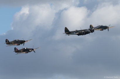 Three Hurricanes are led across the Duxford sky by the Bristol Blenheim.